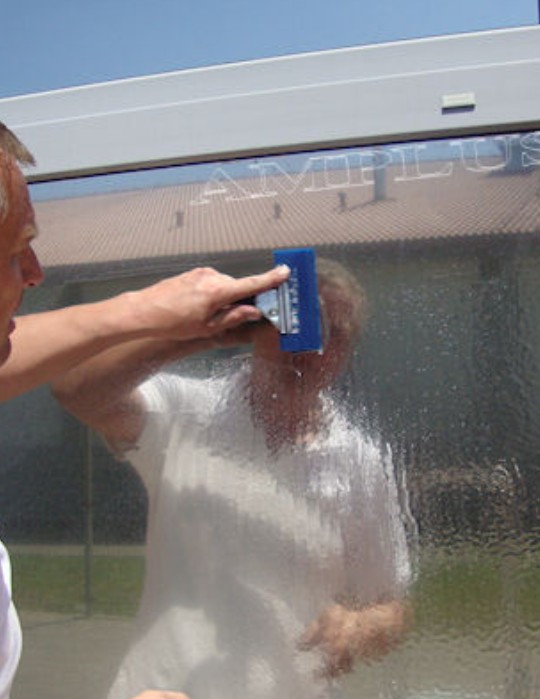 Wyciskanie wody spod folii okiennej gumową raklą