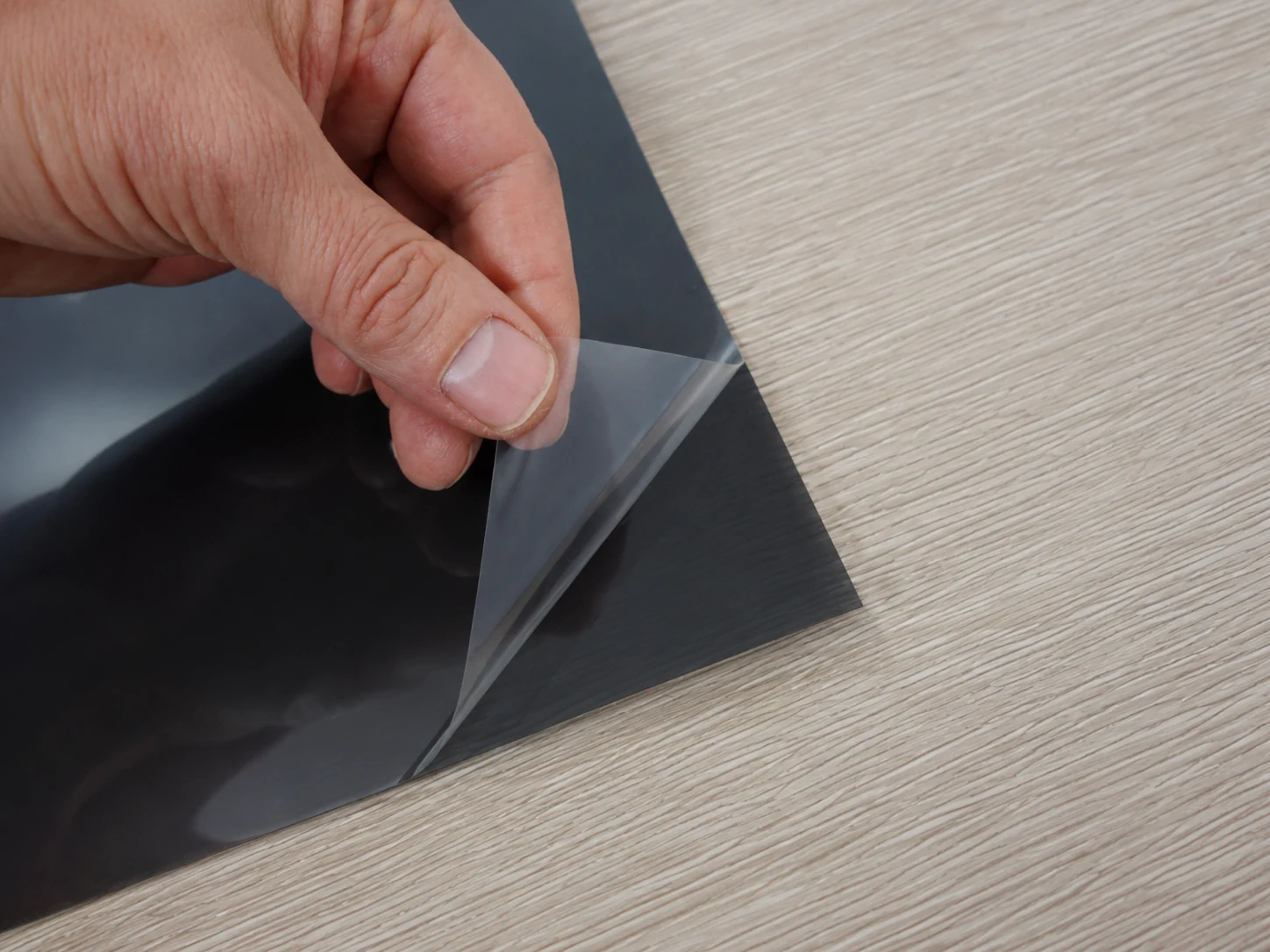 Removing the protective backing from the adhesive side of the privacy filter